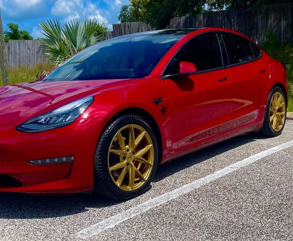 Red Tesla Model 3 with gold wheels